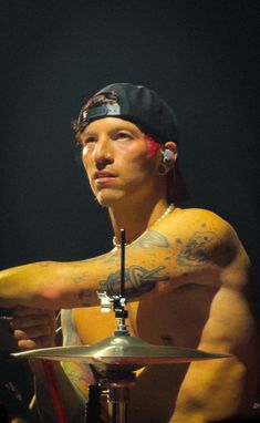 a man with tattoos on his arm playing drums