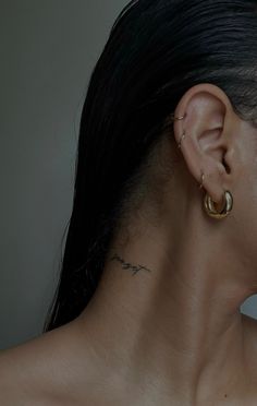 a close up of a person with ear piercings on their ears and behind them is a white wall