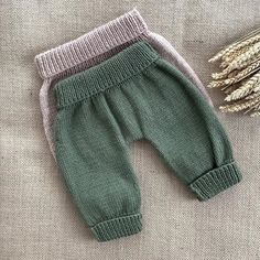 two baby pants sitting on top of a table next to some wheat stalks and a plant