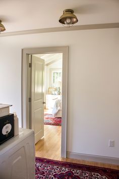 an open door leading to a bedroom with white walls and wood flooring on the other side