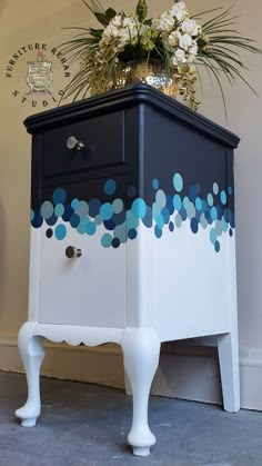 a black and white cabinet with blue circles painted on the side, next to a potted plant