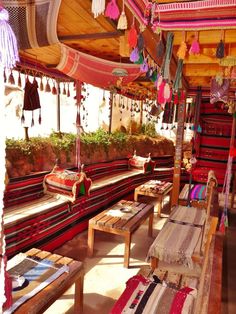 an outdoor area with benches and tables covered in colorful fabric hanging from the ceiling above