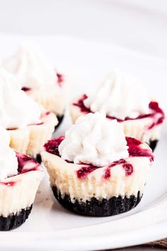 small cupcakes with whipped cream and raspberry topping on a white plate