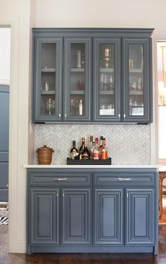 a kitchen with gray cabinets and marble counter tops