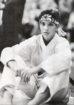 a man sitting on the ground with a tennis racket in his hand while wearing a white outfit