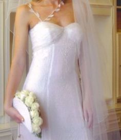 a woman in a white wedding dress holding a bouquet and wearing a bridal veil