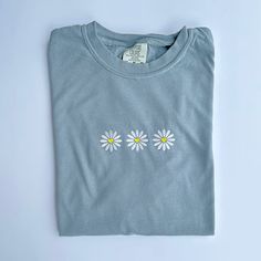 "Retro Daisy Embroidered T Shirt - Comfort Colors Unisex Flowers Shirt - Gift For Her - Shirt Info - -Comfort Colors 1717 Tee in Granite -6.1 oz., 100% ring spun USA cotton -Preshrunk, soft-washed, garment-dyed fabric -Made with sustainably and fairly grown USA cotton and sewn with USA cotton thread -Twill taped shoulder-to-shoulder -Set-in sleeves -Double-needle stitched sleeves and bottom hem -1\" ribbed collar with double-needle topstitched neckline -Comfort colors uses 50% less water than traditional pigment dye processes on pigment dye and color blast garments -Comfort colors®, through Gildan's community investment program, supports education, the environment, humanitarian aid and active living in the communities we do business in Care instructions: -Machine cold wash, inside out, wit White Crew Neck T-shirt With Floral Applique, Floral Applique Short Sleeve Top In Relaxed Fit, Custom Embroidered Short Sleeve Shirt For Summer, Casual Crew Neck T-shirt With Floral Applique, Basic Cotton Tops With Custom Embroidery And Relaxed Fit, Basic Relaxed Fit Top With Custom Embroidery, Blue T-shirt With Embroidered Text For Spring, Blue Custom Embroidery Short Sleeve Top, Blue Short Sleeve Top With Custom Embroidery