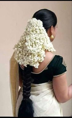 a woman with braids and flowers in her hair is wearing a white sari