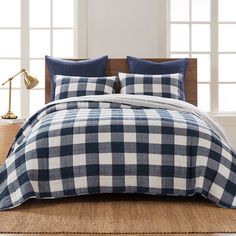 a blue and white checkered comforter set on a bed