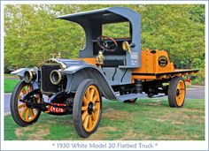 an old fashioned car is parked on the grass