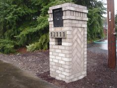 a brick mailbox in front of some trees