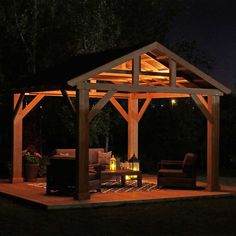 an outdoor gazebo lit up at night with lights on the roof and patio furniture