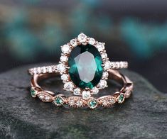 an oval shaped green and white diamond ring on top of a rock with diamonds around it