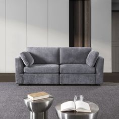 a gray couch sitting on top of a carpeted floor next to a table and chair