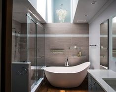 a bathroom with a bathtub, sink and large mirror on the wall next to it