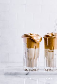 two glasses filled with ice cream on top of a white counter next to each other