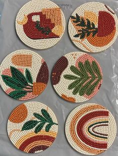 four coasters with beaded designs on them