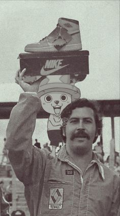 a man holding up two pairs of shoes