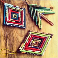 three colorful frames are hanging on a wooden table with string and yarn in them,