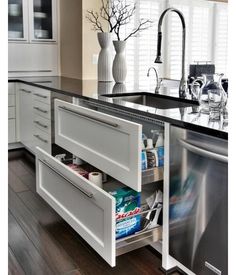 an open dishwasher in a kitchen next to a sink and counter with drawers