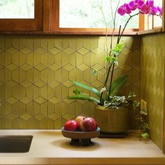 a bowl of fruit sitting on top of a kitchen counter next to a potted plant