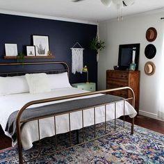 a bedroom with blue walls and white bedding, rugs and wooden dressers