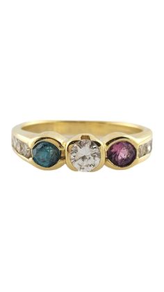 three stone ring in yellow gold with white and blue stones on the sides, set against a plain background