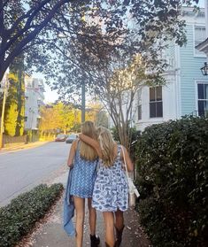 two girls walking down the sidewalk with their arms around each other and one girl holding her head