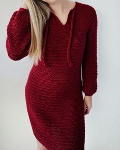 a woman wearing a red knitted dress with hoodie on her head and long blonde hair