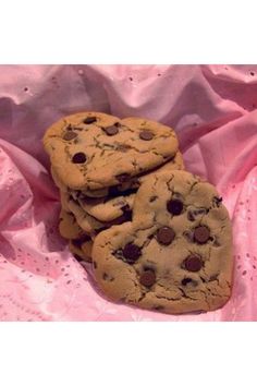 three chocolate chip cookies sitting on top of a pink cloth