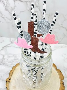 some paper straws are sitting in a jar on a tree stump with black and white stripes