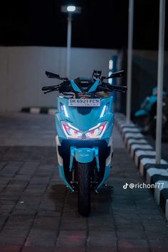 a blue motorcycle parked on the side of a road at night with its lights on