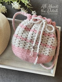 a crocheted pink and white purse sitting on top of a tray next to a straw hat