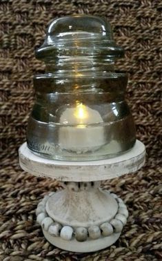 a glass jar sitting on top of a white pedestal with beads around it's base