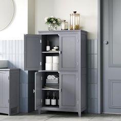 a bathroom with a gray cabinet next to a sink and toilet paper dispenser