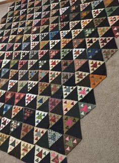 a large quilt is laying on the floor in front of a wall and carpeted area