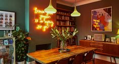 a dining room with green walls, wooden table and two lamps hanging from the ceiling