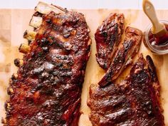 two pieces of barbecue ribs on a cutting board next to a jar of bbq sauce