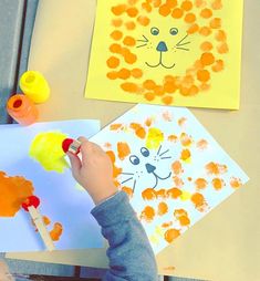 a child is painting on paper with oranges and yellows in the shape of a lion