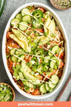 a dish with cucumbers, tomatoes and cheese in it next to two small bowls