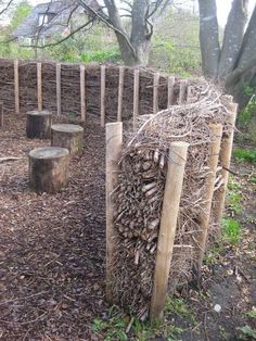 a pile of wood sitting in the middle of a field next to a fence and trees