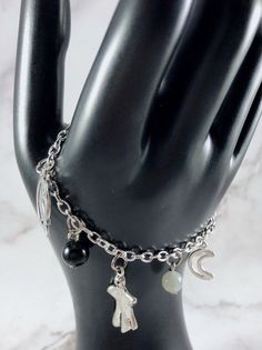 This fun, Melinoe themed charm bracelet is the perfect accessory to showcase your love for the Greek Myths in a subtle way. Charms included: Skull Bone Raven Ghost Moon 3 obsidian and 2 moonstone gemstone beads are included between each charm. Comes in three sizes: Small: 6.5 inches (with extra rings at the end to expand up to 7.5 inches.) Standard: 7.5 inches Large: 8.5 inches Secures with a lobster clasp. Bracelet and charms are made with zinc alloy and beads are natural gemstones. All materia Handmade Symbolic Charm Bracelet For Friendship, Spiritual Metal Charm Bracelet, Handmade Themed Metal Bracelets, Themed Handmade Metal Bracelets, Metal Charm Bracelet With Moon Charm As A Gift, Greek Mythology Jewelry, Mythology Jewelry, Greek Myths, Greek Goddess