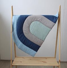 a wooden chair with a blue and grey pillow on it's back, in front of a white wall