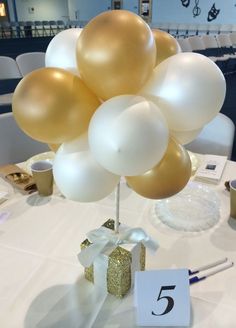 the table is set up with gold and white balloons