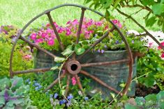 an old wagon with flowers in it is surrounded by greenery and other garden items