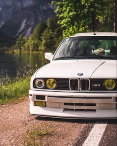 a white car parked on the side of a road next to a body of water