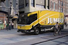 a man riding a bike next to a yellow and black truck on a city street