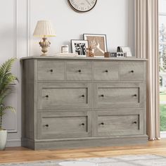 a large gray dresser sitting in a living room next to a clock on the wall