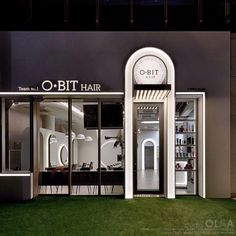 the entrance to an o - bit hair store at night with grass and lights on