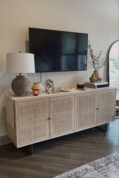 a large flat screen tv mounted on top of a wooden cabinet